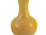 un vase jaune posé sur une surface blanche