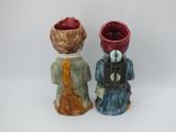 pair of ceramic figurines of two people with a red apple in their hand