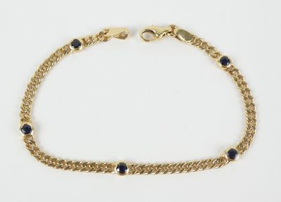 un gros plan sur un bracelet à chaîne en or orné de pierres bleues