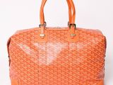 an orange goyard bag with two handles on a white background