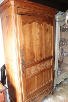 a wooden cabinet with a glass door in the corner of a room