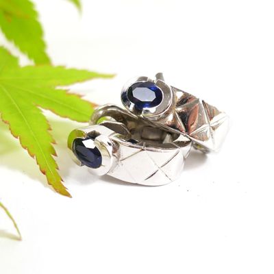 a silver ring with a blue stone on top of a leaf