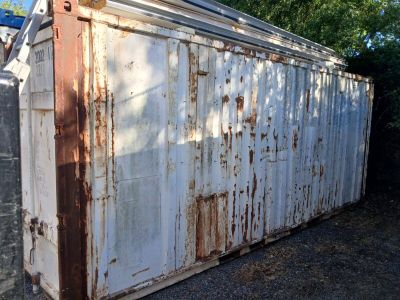 a rusted out storage container sitting in the middle of a yard