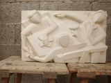 a large white sculpture on a wooden bench in front of a brick wall