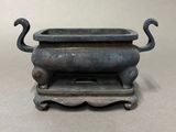 an old bronze incense burner with a cat on top of it