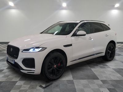 un SUV Jaguar blanc garé dans un showroom au sol carrelé