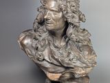 sculpture représentant le buste d'un homme aux cheveux bouclés, posée sur un socle