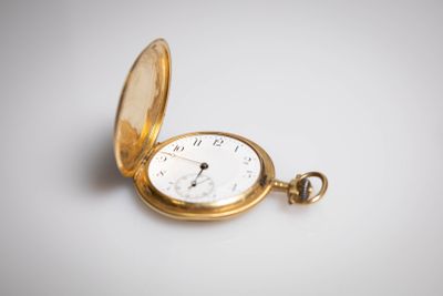 une vieille montre de poche avec une chaîne, posée sur une surface blanche