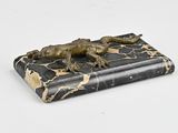 une statue représentant un lézard allongé sur un livre
