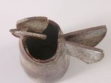 a small vase with a spoon in it on a white surface