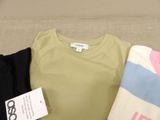 three t - shirts on a couch with a tag on it