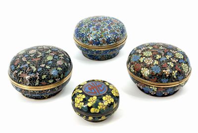 four small round boxes with floral designs on them sitting on a white surface