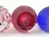 four different colored glass vases sitting next to each other on a white surface