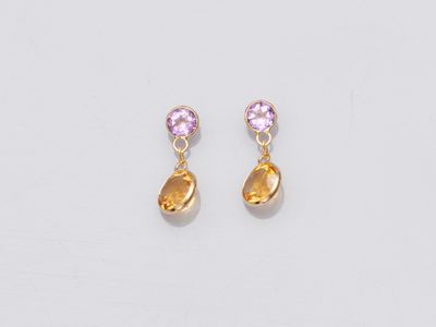une paire de boucles d'oreilles en cristal jaune et rose posées sur une surface blanche