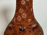 a brown vase with flowers on it sitting on a table