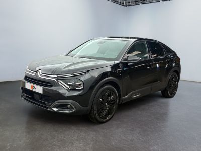 Une voiture noire est garée dans une grande pièce au sol noir.