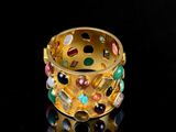 a gold ring with multi colored stones on a black surface