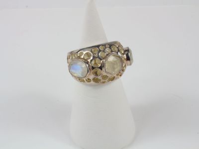une bague en or et en argent ornée de lunes, posée sur un présentoir blanc pour bagues