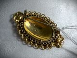 an image of a gold broochle with a pin in it