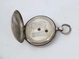 a silver pocket watch with a key in it