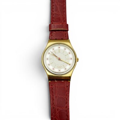 un gros plan d'une montre posée sur une surface blanche, avec un bracelet rouge