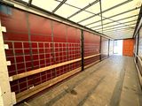 a long hallway with a red wall and a metal fence
