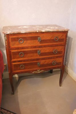 a small chest of drawers next to a chair in a room