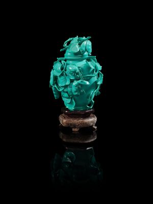 un vase en jade vert sculpté, posé sur un socle, sur fond noir