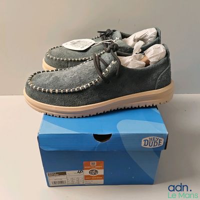 men ' s grey sued moccali shoes on top of a blue box