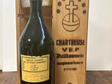 une vieille bouteille de vin dans une caisse en bois, à côté d'une bouteille de vin