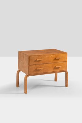 an image of a small wooden chest of drawers on a white surface