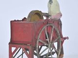 a toy of a man sitting in a wagon with a wheel