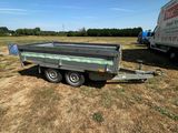 une remorque vide garée dans un champ, avec un camion derrière