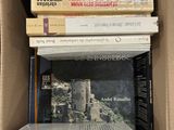 Les livres sont empilés dans une boîte en carton posée sur une table.