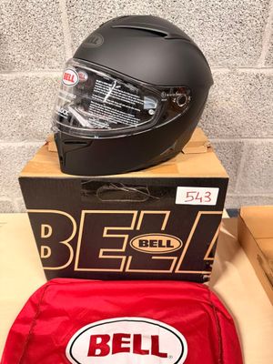 bell motorcycle helmet and helmet bag sitting on a table next to a brick wall