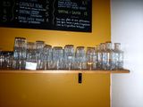 bottles and glasses on a shelf in front of a chalk board