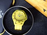 a yellow watch sitting in a black box next to a baseball bat