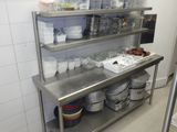 une étagère en acier inoxydable sur laquelle sont posés des plats, dans une cuisine