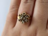 a woman ' s hand holding a ring with a flower design