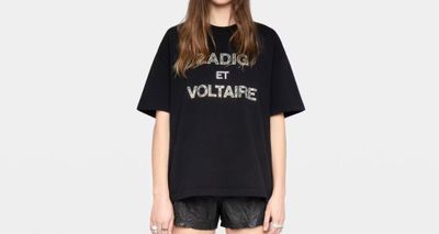 une femme portant un t-shirt noir avec un slogan imprimé dessus