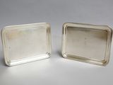 a pair of silver trays with handles on each side