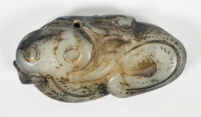 un objet en pierre sur lequel est représenté un poisson, posé sur une surface blanche