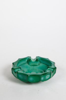 une photo d'un cendrier en verre vert posé sur une table blanche