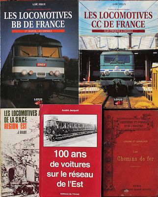 plusieurs livres posés sur une table, avec un train en arrière-plan