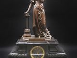 une statue de femme tenant une horloge sur une table
