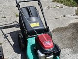 a lawn mower sitting on the sidewalk next to other lawn mowers