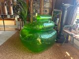 a large green vase sitting on the floor next to a lamp