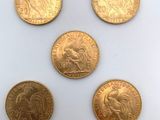 cinq pièces d'or présentant des motifs différents, posées sur un fond blanc