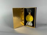 flacon de parfum en verre jaune présenté dans un coffret doré muni d'un couvercle noir