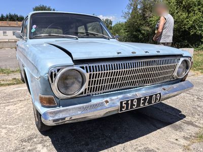 a man standing next to an old car in a parking lot